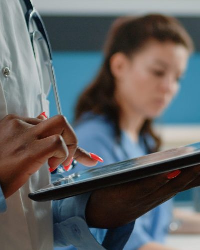 A doctor explaining his procedure on his computer to the nurse, who is also typing on electronic devices