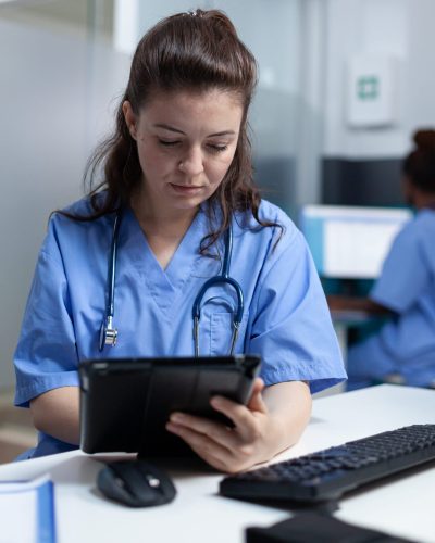 A nurse at her desk working on a tablet