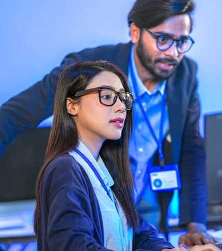 Two IT specialists working in an office with blue lighting